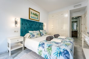 Een slaapkamer met een bed, nachtkastje, garderobe en een schilderij aan de muur.