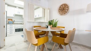 A dining area with a round table, yellow chairs, a clock, and a plant.