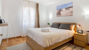 Un dormitorio ordenado con cama, mesita de noche, lámpara y un cuadro en la pared.
