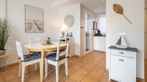 A dining area with a round table, two chairs, a potted plant, a wall clock, and a cabinet with drawers. - Apartment 'El Puerto I 1-3' with Shared Pool, Wi-Fi and Air Conditioning (Cala D'or)
