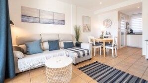 A modern living room with a sofa, dining table, and kitchen area. - Apartment 'El Puerto I 1-3' with Shared Pool, Wi-Fi and Air Conditioning (Cala D'or)