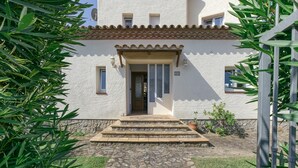 A two-story building with a stone staircase leading to the entrance, a tiled roof, and a small garden area. - Villa 'Casa Flores' with Mountain Views, Shared Pool, and Wi-Fi (Vilacolum)