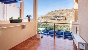 A balcony with a view of a rocky hillside, a potted plant, and a metal railing. - Vacation Apartment 'Paraíso Taurito' with Sea View, Terrace, Shared Pool & Wi-Fi (Taurito)