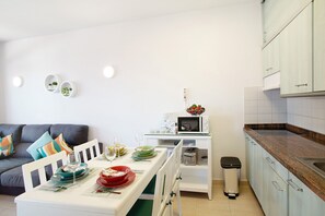 A modern kitchen with white cabinets, a dining table set with plates and glasses, and a microwave on the counter.