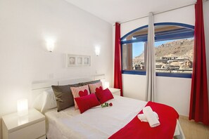Une chambre d’hôtel avec un lit, une table de chevet, une fenêtre avec des rideaux et une vue sur un immeuble.