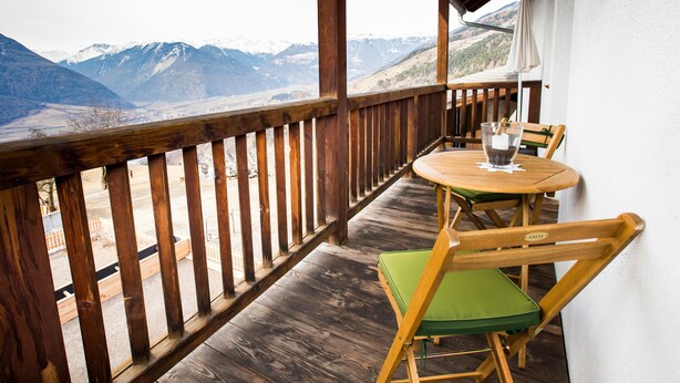 A wooden deck with a table and chairs, overlooking a mountainous landscape. - Apartment 'Vernalhof Apt Sunnaseit' with Mountain View, Shared Terrace and Wi-Fi (Sluderno)