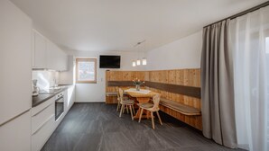 A modern kitchen with a dining area, wooden paneling, a flat-screen TV, and a window with a view. - Apartment 'Vernalhof Apt Sunnaseit' with Mountain View, Shared Terrace and Wi-Fi (Sluderno)