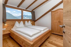 Un letto in legno in una stanza con vista sulle montagne, un armadio in legno e un pavimento in legno.
