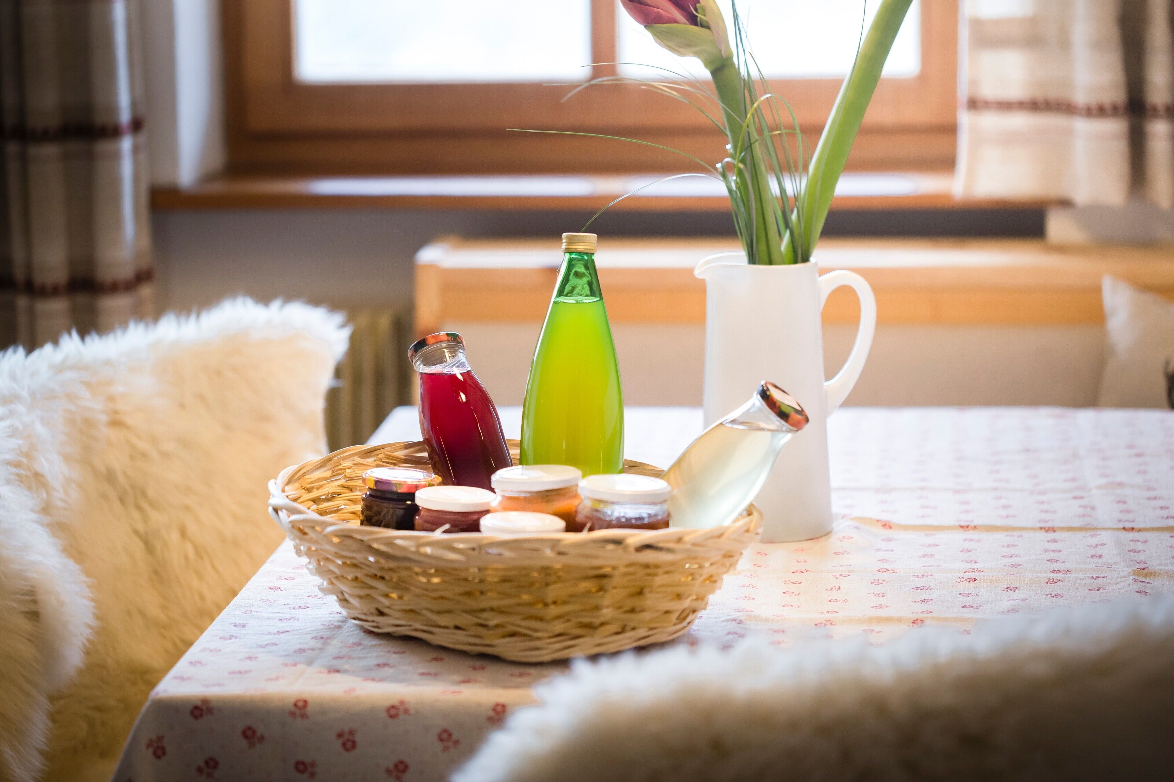 Ein Tisch mit einem Tablett voller Gläser, einer grünen Flasche und einer weißen Karaffe auf einer Tischdecke.