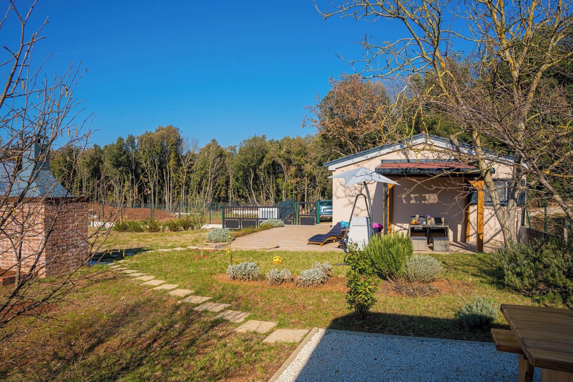 Ein kleines Haus mit Terrasse, Pool und Garten.