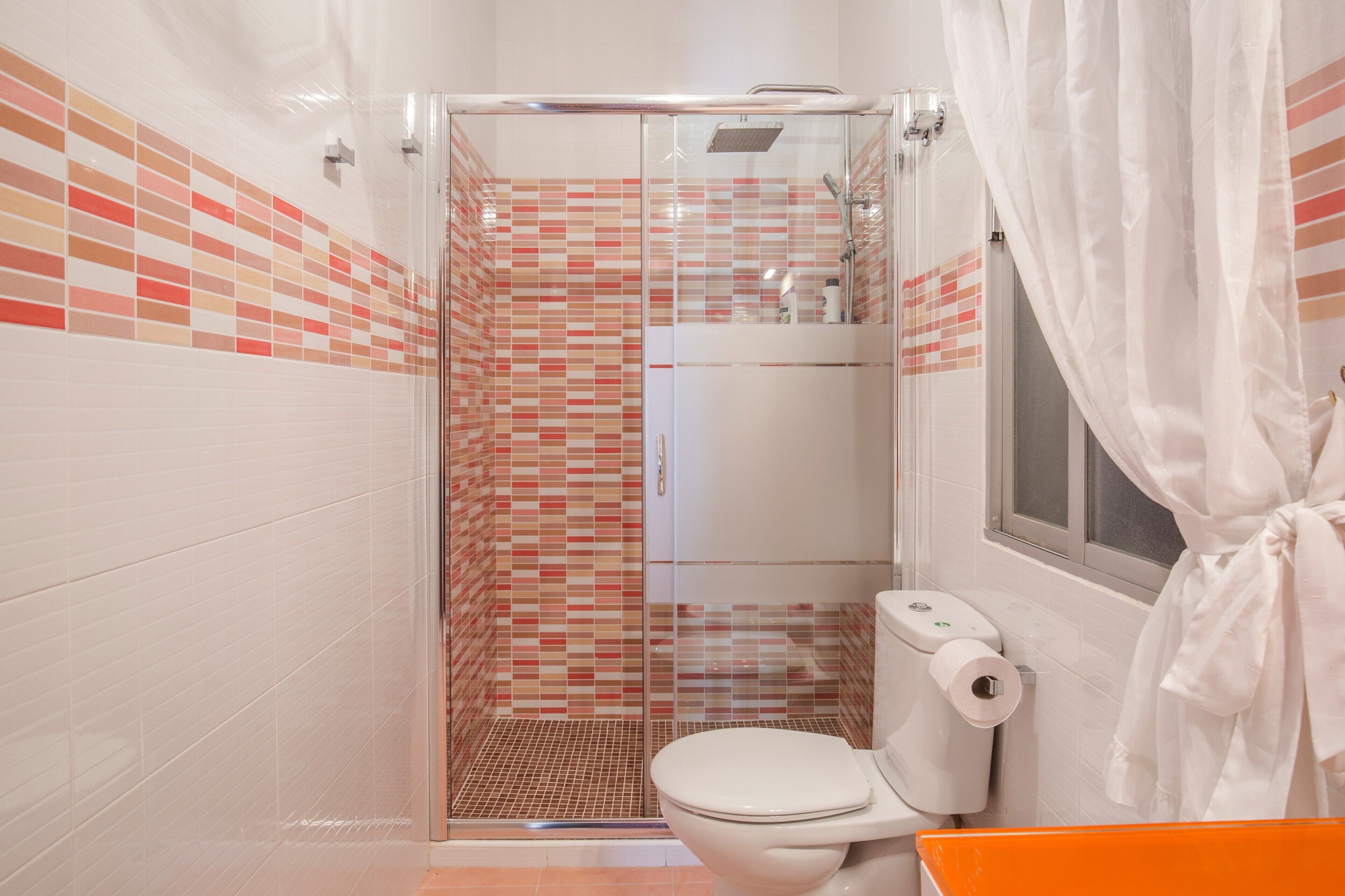 Une salle de bain avec une douche à parois de verre, des toilettes et un lavabo.