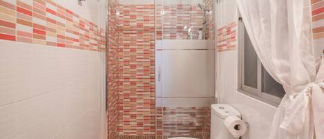 Une salle de bain avec une douche à parois de verre, des toilettes et un lavabo.