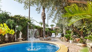 A circular pool with a fountain, surrounded by potted plants and a statue. - Studio 'Alojamiento Ruizo' with Mountain Views, Shared Pool and Wi-Fi (Lorca)