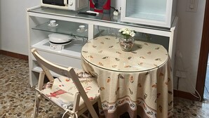 A compact living space with a microwave, a small refrigerator, a television, a glass table with a patterned tablecloth, and a chair. - Studio 'Alojamiento Ruizo' with Mountain Views, Shared Pool and Wi-Fi (Lorca)