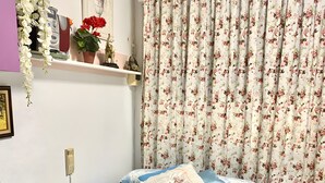 A bedroom with a bed, a dresser, a shelf with decorative items, and a curtain with a floral pattern. - Studio 'Alojamiento Ruizo' with Mountain Views, Shared Pool and Wi-Fi (Lorca)