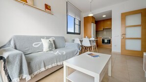 A modern living room with a sofa, a coffee table, and a kitchen area in the background. - Holiday Apartment "Ferran" with Private Terrace, Balcony & Wi-Fi (Deltebre)