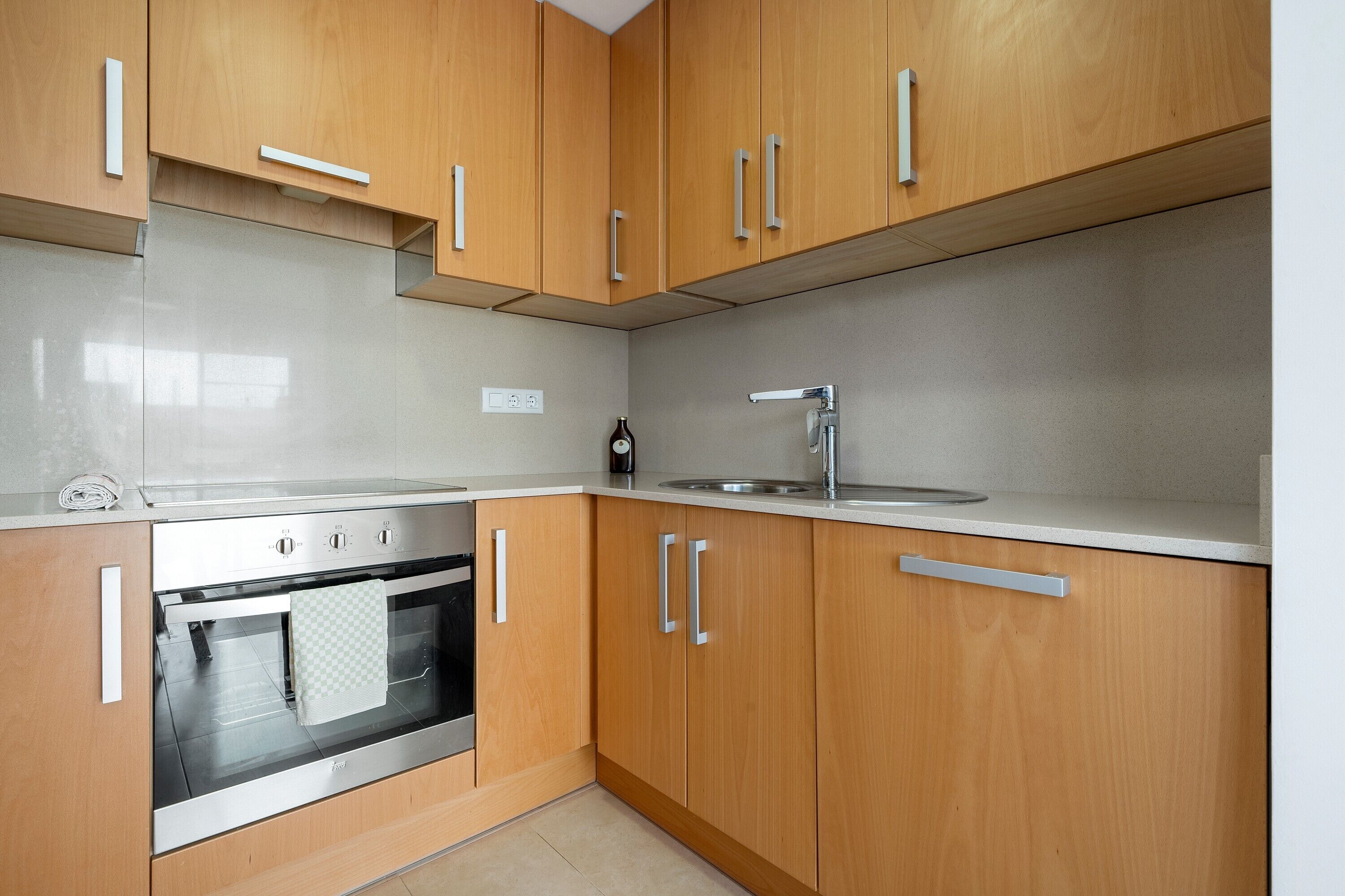 Una cocina con armarios de madera, un horno de acero inoxidable y un lavamanos.