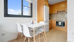 A modern kitchen with white cabinetry, a built-in oven, and a dining area with a white table and chairs. - Holiday Apartment "Ferran" with Private Terrace, Balcony & Wi-Fi (Deltebre)