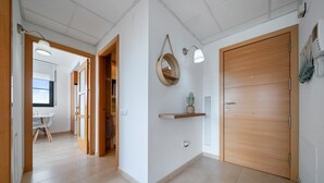 A hallway with a wooden door, a wall-mounted shelf with a plant, and a hanging lamp. - Holiday Apartment "Ferran" with Private Terrace, Balcony & Wi-Fi (Deltebre)