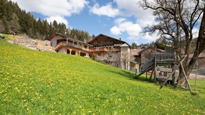 A chalet with a wooden exterior, a balcony, and a staircase leading up to the entrance. - Holiday Apartment "Pischlhof Apt Lärche" with Mountain View, Balcony & Shared Garden (Aldino)
