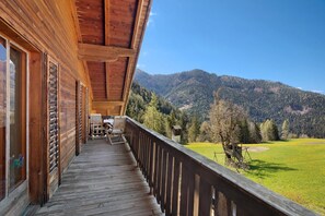 Een houten balkon met uitzicht op een bergachtig landschap.