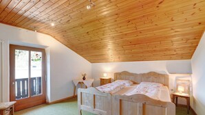 A bedroom with a wooden ceiling, a bed, a nightstand, a chair, and a window with a view. - Holiday Apartment "Pischlhof Apt Lärche" with Mountain View, Balcony & Shared Garden (Aldino)