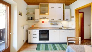 A compact kitchen with white cabinets, a built-in oven, and a small countertop. - Holiday Apartment "Pischlhof Apt Lärche" with Mountain View, Balcony & Shared Garden (Aldino)