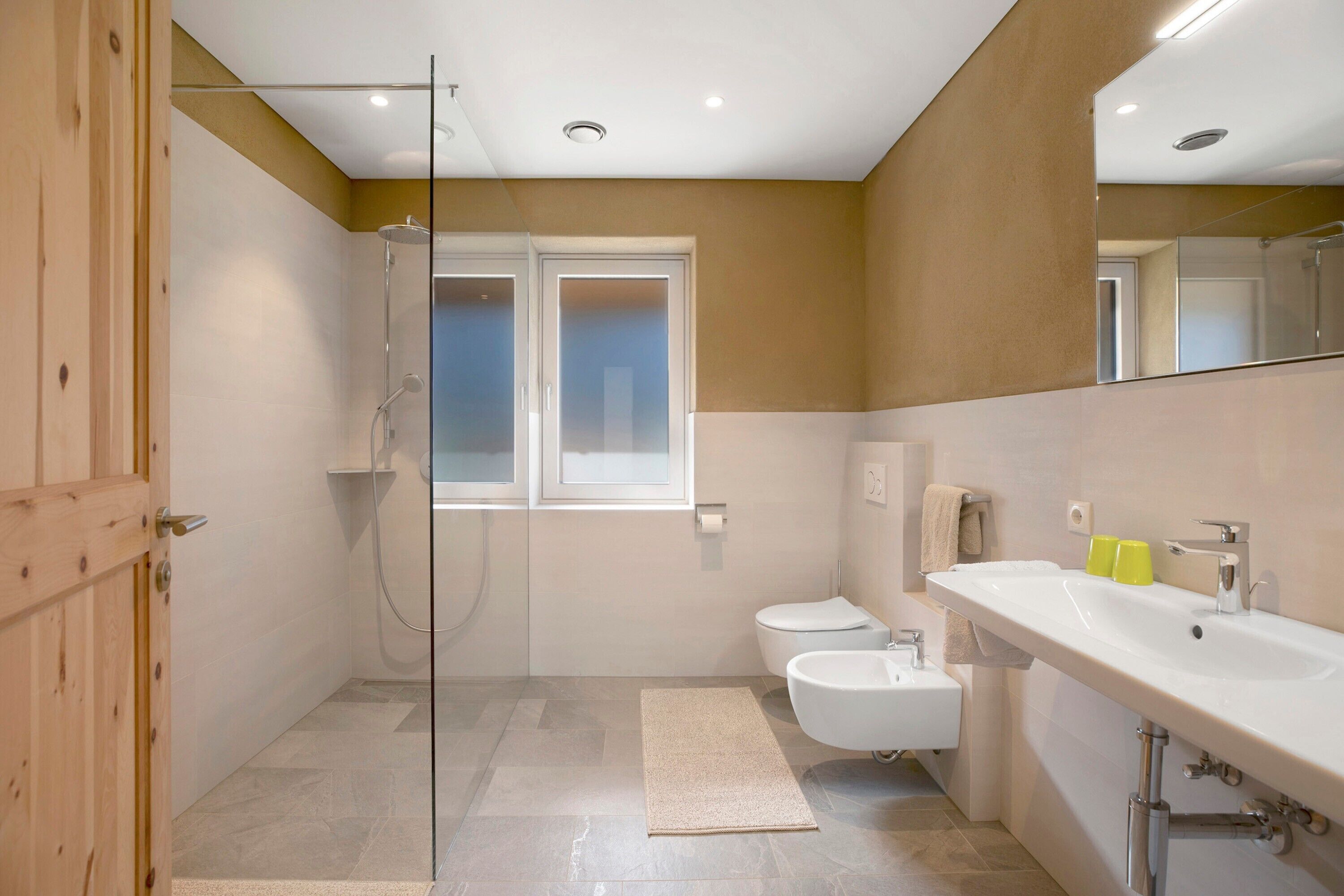 A modern bathroom with a shower, toilet, sink, and a large mirror.