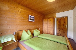 A wooden cabin room with a bed, a table, and a door.