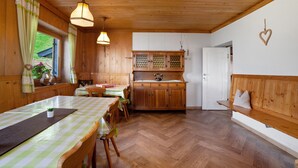 Un interior de madera con una mesa de comedor, sillas, un banco, un armario y una decoración con forma de corazón colgante.