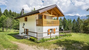 A chalet-style building with a balcony, surrounded by a wooden fence, set in a mountainous area with a clear sky. - Chalet 'Baita Bocheto' with Balcony & Terrace (Levico Terme)