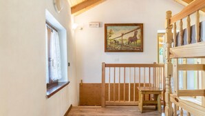 A wooden staircase with a railing, a wooden bench, a painting of horses on the wall, and a window with curtains. - Chalet 'Baita Bocheto' with Balcony & Terrace (Levico Terme)