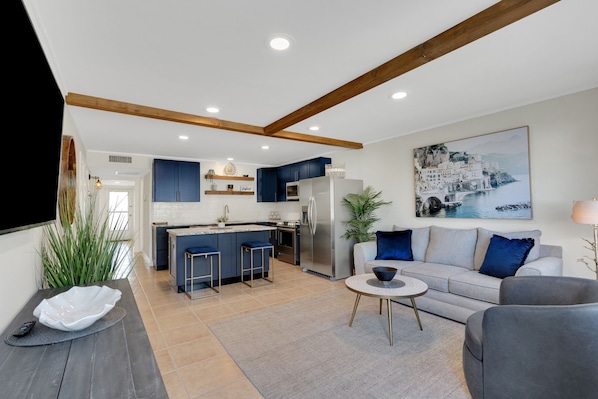 A modern kitchen with blue cabinets, a central island, and a stainless steel refrigerator.