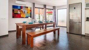 A modern kitchen with a stainless steel refrigerator, a dining table with benches, and a colorful abstract painting on the wall. - Villa "Can Olivera" close to the Sea with Private Pool & Wi-Fi (Ibiza)