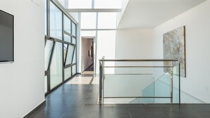 A modern interior with a glass railing, a large window, and a minimalist art piece. - Villa "Can Olivera" close to the Sea with Private Pool & Wi-Fi (Ibiza)