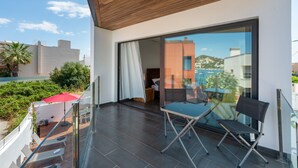 A modern balcony with a wooden ceiling, a glass door leading to a room, and a view of buildings and greenery. - Villa "Can Olivera" close to the Sea with Private Pool & Wi-Fi (Ibiza)