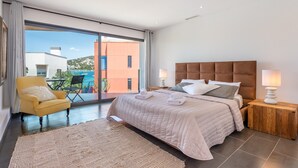 A modern bedroom with a large bed, a yellow armchair, and a view of the outside. - Villa "Can Olivera" close to the Sea with Private Pool & Wi-Fi (Ibiza)