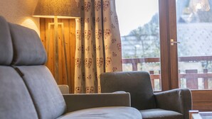 A room with a sofa, a chair, a lamp, and a view of a snowy landscape through a window.