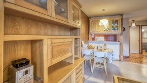 A kitchen with wooden cabinets, a dining table, chairs, and a microwave.
