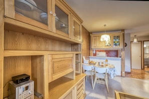 A kitchen with wooden cabinets, a dining table, chairs, and a microwave.