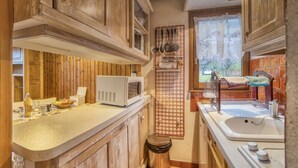 A kitchen with wooden cabinets, a microwave, and a sink.