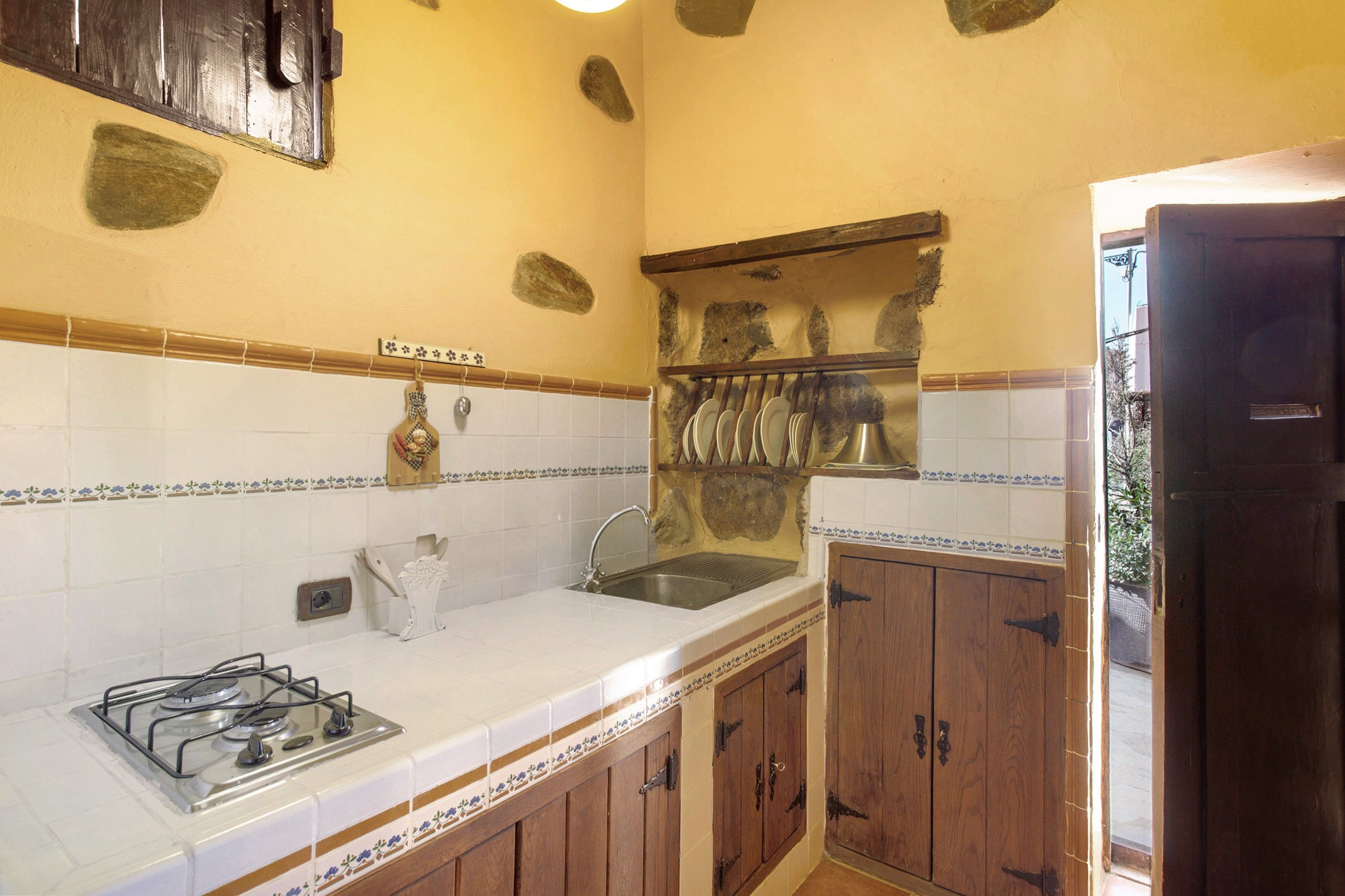 A kitchen with a gas stove, sink, and wooden cabinets.