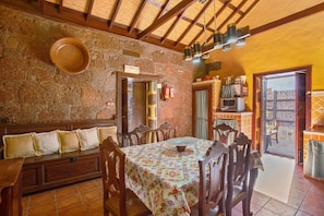 A dining area with a wooden table and chairs, a stone wall, and a ceiling with wooden beams. - Country House 'Bentayga Sensation' with Private Pool (Tejeda)