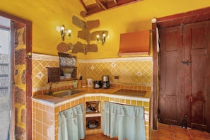 A kitchen with a yellow wall, a wooden door, and a tiled backsplash. - Country House 'Bentayga Sensation' with Private Pool (Tejeda)