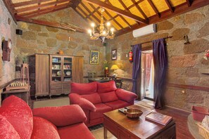 Una habitación acogedora con pared de piedra, muebles de madera, una araña y una chimenea.