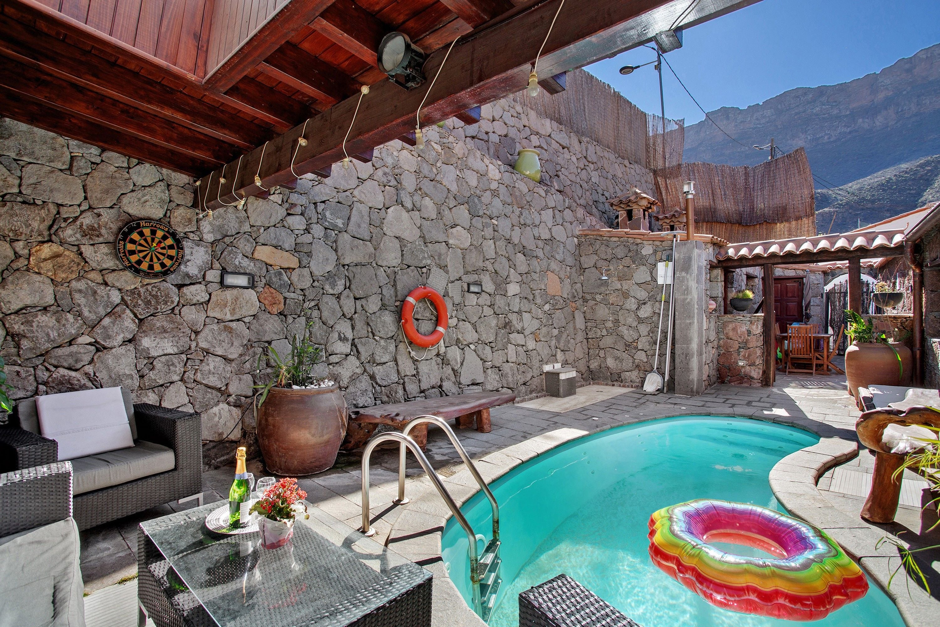 Zona de piscina con paredes de piedra, un dardo y un flotador.