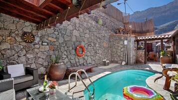 Zona de piscina con paredes de piedra, un dardo y un flotador.