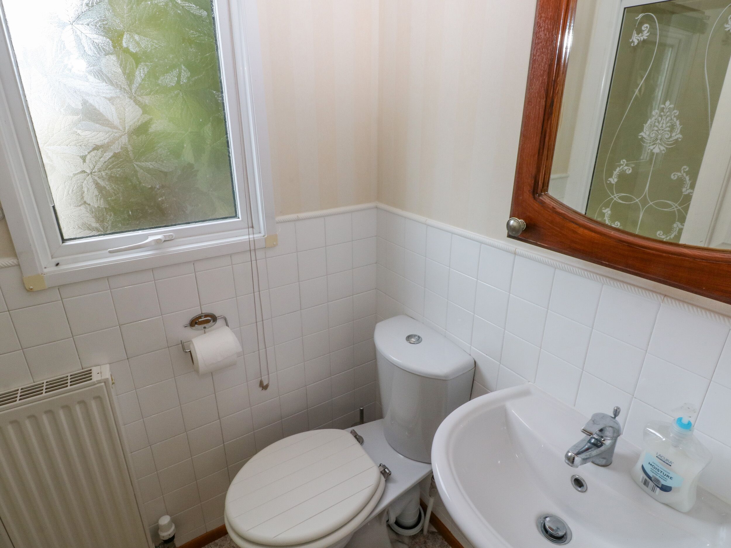 A small bathroom with a toilet, sink, and window.