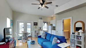Ein modernes Wohnzimmer mit einem blauen Sofa, einem weißen Couchtisch und einem Deckenventilator.