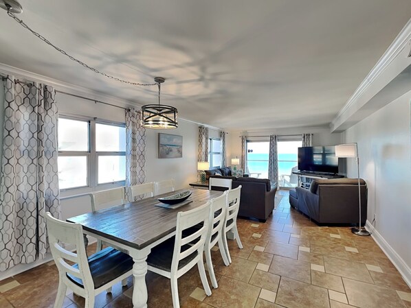 Une chambre moderne équipée d’une table à manger, de chaises, d’un canapé, d’une télévision et d’un balcon offrant une vue sur la mer.